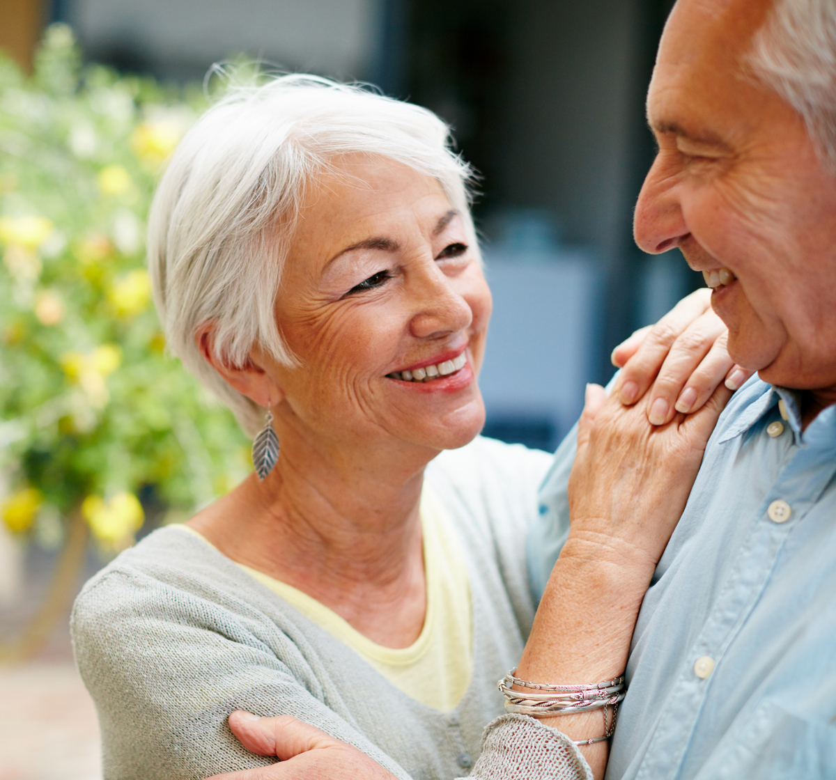An elderly couple smile at each other